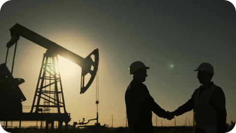 Dos hombres parados frente a una plataforma petrolera.