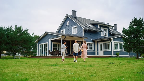 couple walking outside of new home with real estate agent