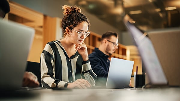 Woman employee working on a laptop with a team