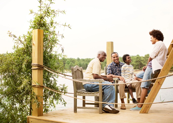 Photo of a multigenerational family sitting on a dock at the lake