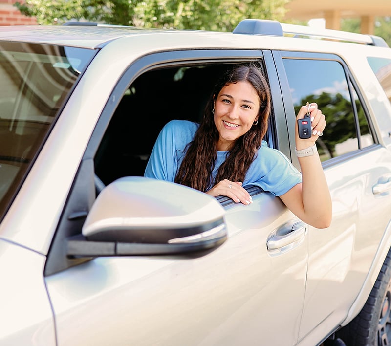 woman in new car holding up her keys